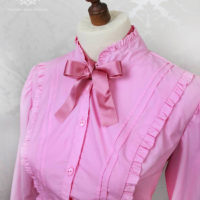 Rüschenbluse in Pink mit Schleife und Stehkragen an einer Puppe